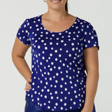 Size 12 curvy woman wears the Sawyer top a scoop neckline top on a polka dot print with a cobalt base. Styled back with a black Cassidy skirt.Made in Australia for women size 8 to 24.