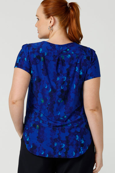 Back view of s curvy, size 12 woman wearing a cobalt abstract jersey print, Round neck top with short sleeves. A good top for summer casual wear, or style tucked as a workwear top. Shop made in Australia tops in petite to plus sizes online at Australian fashion brand, Leina & Fleur.