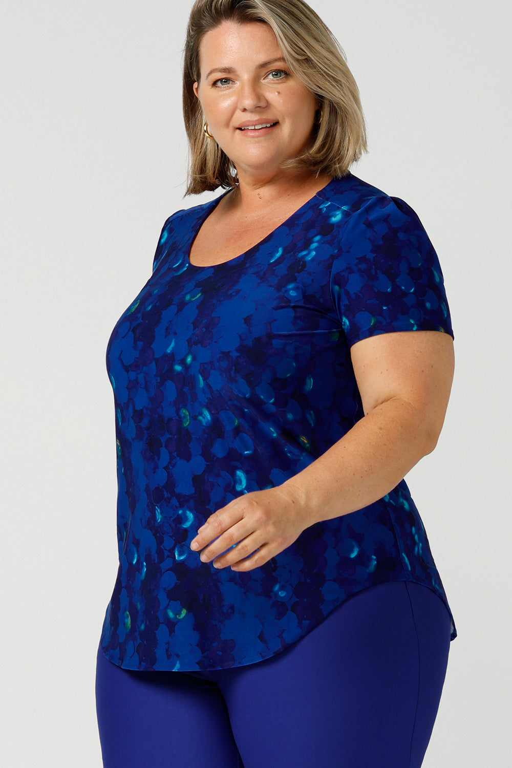 A plus size, size 18 woman wears a cobalt abstract jersey print, Round neck top with short sleeves. A good top for summer casual wear, or style tucked as a workwear top. Shop made in Australia tops in petite to plus sizes online at Australian fashion brand, Leina & Fleur.