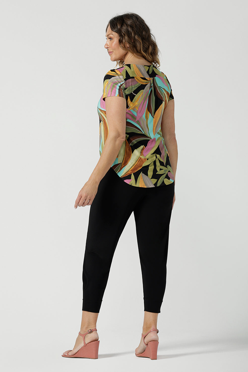 Back view of a size 10 woman wears the Sawyer Top in jersey with Zanzibar print. A multi coloured print with a black base and beautiful bright colours. Made in Australia for women size 8-24. Styled back with the Indi Pant in Black.  