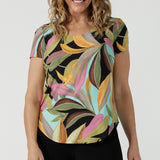 A size 10 woman wears the Sawyer Top in jersey with Zanzibar print. A multi coloured print with a black base and beautiful bright colours. Made in Australia for women size 8-24. 