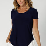 With its simple yet elegant scoop neckline, it offers a flattering fit for a variety of body shapes, making it a wardrobe staple. Ideal for layering, it works brilliantly under Leina & Fleur suiting jackets and cardigans, adding a refined, polished look to your outfit. Model wears navy workwear top with short cap sleeves.