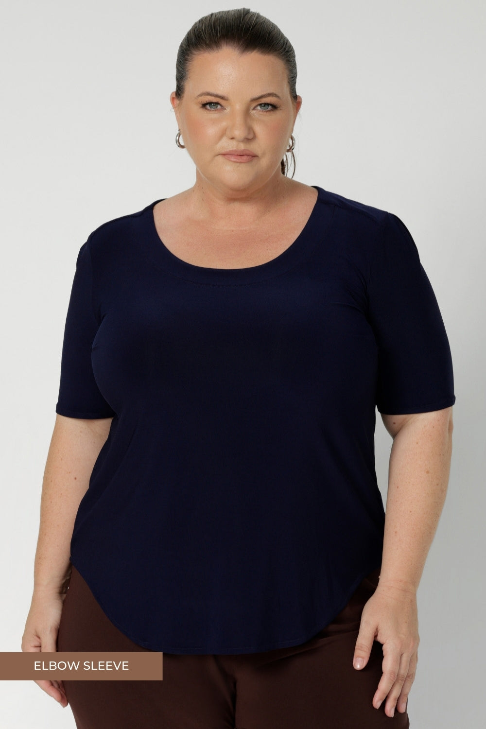 Size 18 woman wears navy workwear top, that features scoop neckline, elbow length sleeves and shirttail hemline. It’s a must-have for any modern woman’s wardrobe, designed to be as practical as it is chic, and a perfect choice for those building a sustainable workwear capsule. Proudly designed and made in Australia in sizes 8-24.