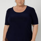 Size 18 woman wears navy workwear top, that features scoop neckline, elbow length sleeves and shirttail hemline. It’s a must-have for any modern woman’s wardrobe, designed to be as practical as it is chic, and a perfect choice for those building a sustainable workwear capsule. Proudly designed and made in Australia in sizes 8-24.