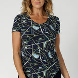 This versatile Scoop Neck Top is the perfect blend of style and practicality, designed to effortlessly transition between smart and casual occasions. Size 12 model wears cap sleeved top in Willow print that features a navy base with abstract design in shades of blue, green and white.