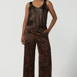 A woman wears the Sloane Pant in Bronze Animal. A satin straight leg waisted pant with pockets and a zip front. Made in high fashion Animal print fabric. Petite to plus size women size 8-24. 