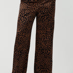 A woman wears the Sloane Pant in Bronze Animal. A satin straight leg waisted pant with pockets and a zip front. Made in high fashion Animal print fabric. Petite to plus size women size 8-24. Styled back with the Pele Shirt in Bronze animal.