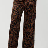 A woman wears the Sloane Pant in Bronze Animal. A satin straight leg waisted pant with pockets and a zip front. Made in high fashion Animal print fabric. Petite to plus size women size 8-24. Styled back with the Pele Shirt in Bronze animal.