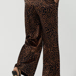 Back view of a woman wears the Sloane Pant in Bronze Animal. A satin straight leg waisted pant with pockets and a zip front. Made in high fashion Animal print fabric. Petite to plus size women size 8-24. Styled back with the Pele Shirt in Bronze animal.