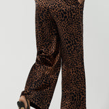 Back view of a woman wears the Sloane Pant in Bronze Animal. A satin straight leg waisted pant with pockets and a zip front. Made in high fashion Animal print fabric. Petite to plus size women size 8-24. Styled back with the Pele Shirt in Bronze animal.