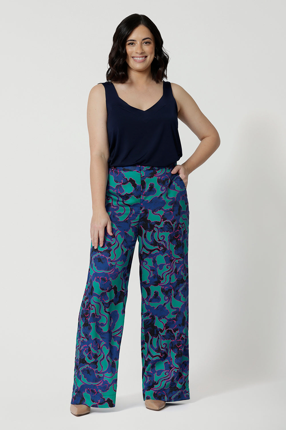 Full body shot image of a petite woman wearing wide leg printed pant and navy cami top. The abstract design of the set displays navy, pink and aqua blue colours. This Australian made shirt and pant set is made from satin rayon fabric that is breathable and comfortable. Leina and Fleur is a women’s clothing company that actively stocks plus sizes & petite sizes ranging from 8 to 24.