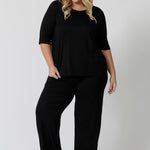 The ultimate outfit for comfortable loungewear, a size 18 woman wears straight wide leg black bamboo lounge pants with a black bamboo slouchy tee top.  Thermo-regulating and breathable this is a great pyjama set for night sweats and hot flushes. Shop plus size lounge and sleepwear online at L&F Australia.