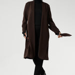 The Sorel Trench Coat is expertly tailored with a modern, sophisticated silhouette that elevates any wardrobe. Size 10 woman wears winter coat crafted from a luxurious winter-weight Modal fabric over long length black pants, black turtle neck, and high heel boots for an elevated workwear look. 