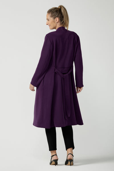 Back view of a size 10 woman wearing the Sorel Trenchcoat in Amethyst. Inner seam pockets with, long sleeves with wrap tie. Made in Australia using soft modal scuba material. Made in Australia for women size 8 - 24.