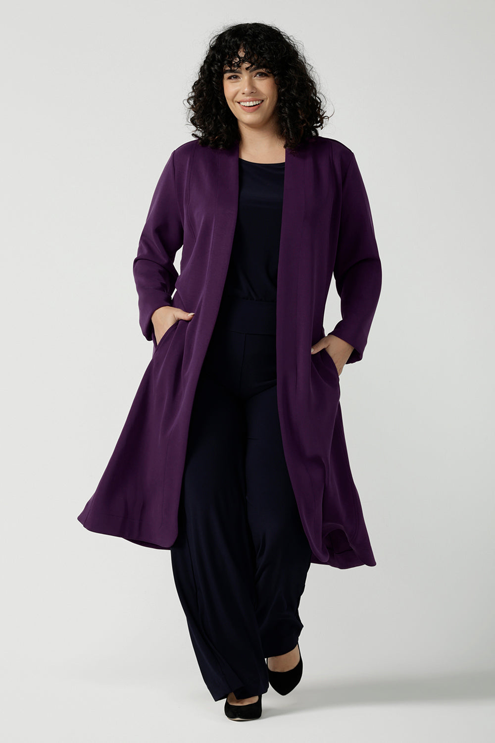 Size 18 woman wears the Sorel Trenchcoat in Amethyst. Inner seam pockets with, long sleeves with wrap tie. Made in Australia using soft modal scuba material. Made in Australia for women size 8 - 24.