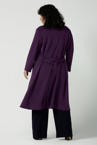 Back view of a size 18 woman wears the Sorel Trenchcoat in Amethyst. Inner seam pockets with, long sleeves with wrap tie. Made in Australia using soft modal scuba material. Made in Australia for women size 8 - 24.
