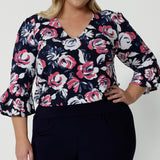 Close up image of plus sized model wearing a V neck floral top. Floral fabric is made of easy care dry touch jersey. 3/4 sleeved top was made in Australia by Australian and New Zealand women. Sizes in this blouse vary from 8-24. Leina and Fleur is woman fashion brand that stocks both petite and plus sizes. Shop now the Tahlia top