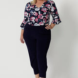 Full body view of plus sized woman. Wearing a 3/4 sleeved shirt with a floral pattern. Made of high quality dry touch jersey fabric. Work wear shirt has pink and white roses on a navy coloured base. This shirt is breathable, easy to care for and Australian made. Made by woman in Australia and New Zealand. Leina and Fleur is an online woman’s clothing brand that has sizes from 8 to 24 including petite & plus sizes.