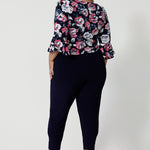 Back view of plus sized woman wearing a dry touch jersey fabric skirt. 3/4 length flutter sleeved top has a colourful print of white and pink roses on navy base. This comfortable work wear skirt is great for both casual wear and dressed up for any occasion. This easy care skirt is made in Australia by Australian and New Zealand women. Leina & Fleur is a woman’s fashion label that stocks sizes from 8 to 24. Shop this comfortable skirt in plus size and petite sizes. 