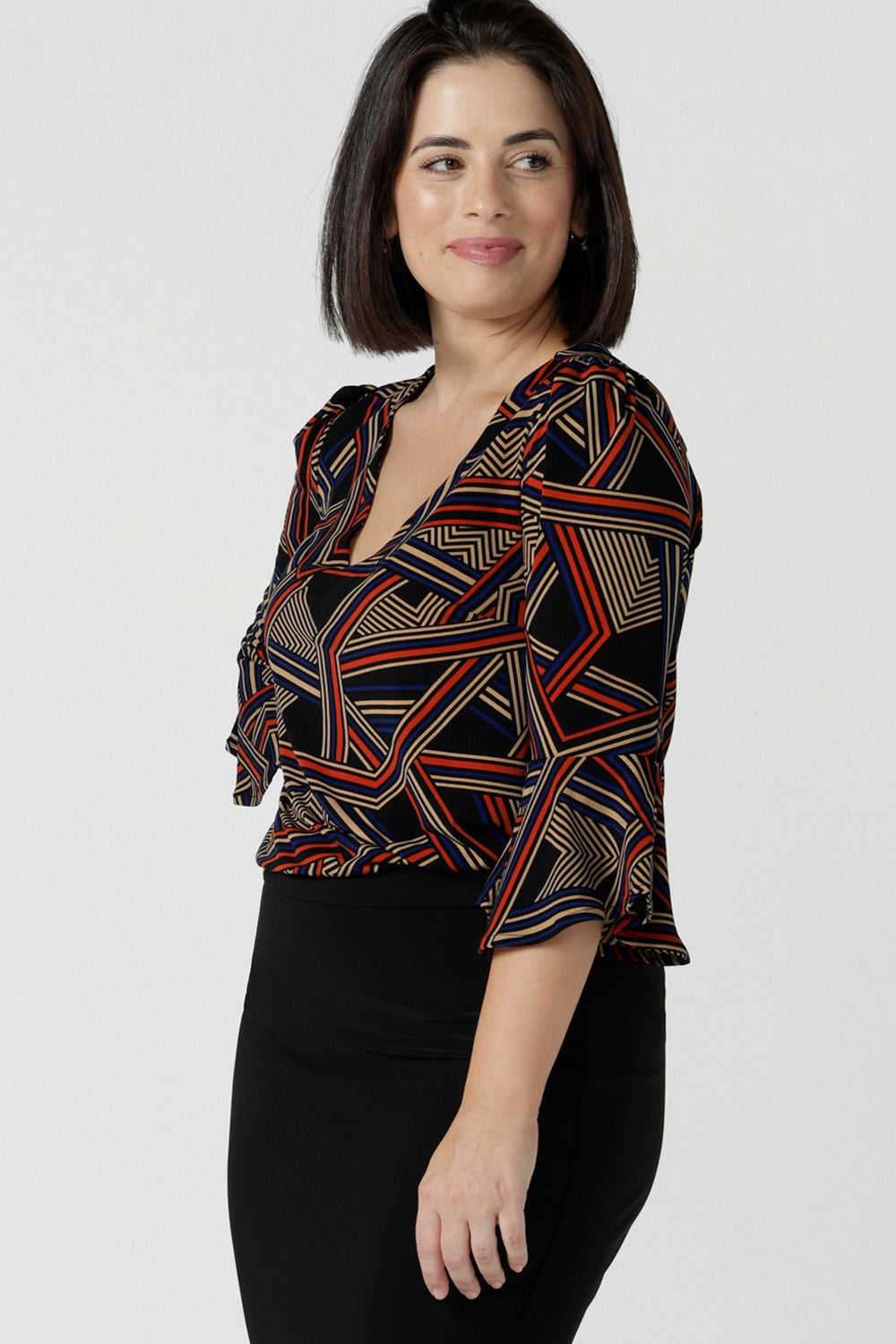 Size 10 Woman wears the V-neck Tahlia top with a fluted sleeve, gathered sleeve head and v-neckline. Easy care jersey work top for women. Styled back with Black tube fitted skirt. Professional workwear for women. Made in Australia size inclusive for petite to plus size 8 - 24.