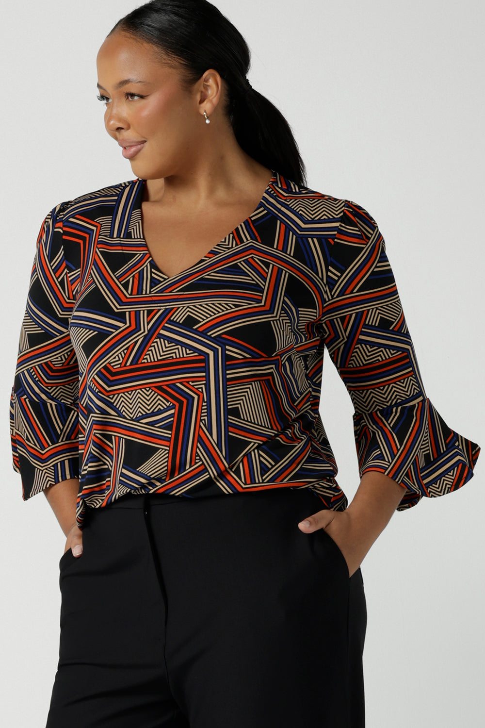 Close up of a size 16 Woman wears the V-neck Tahlia top with a fluted sleeve, gathered sleeve head and v-neckline. Easy care jersey work top for women. Styled back with Black tube fitted skirt. Professional workwear for women. Made in Australia size inclusive for petite to plus size 8 - 24.