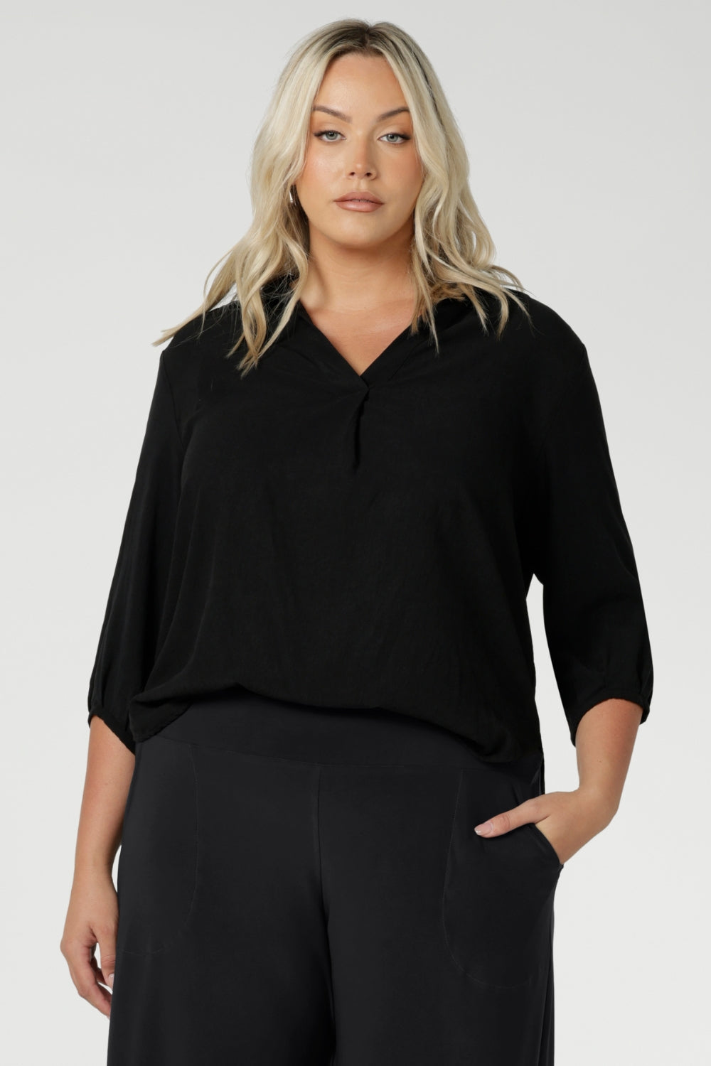 Plus size woman wears Graphite coloured woven shirt with collar and tailored pleat with navy workwear pants and black heels for an elevated corporate look. Made from sustainable Tencel fabric in Australia for petite and plus size woman sizes 8-24. 