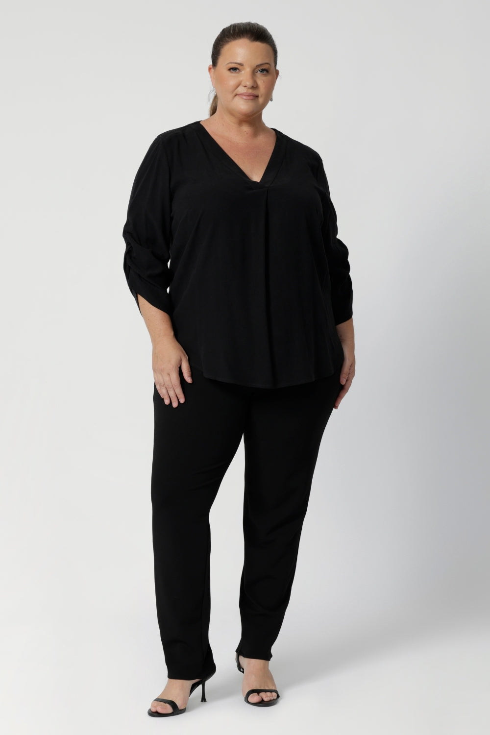 Size 18 model wears v neck blouse. The back neckline is finished with a facing and a neat tailored pleat for subtle detail. Available in sizes 8-24.