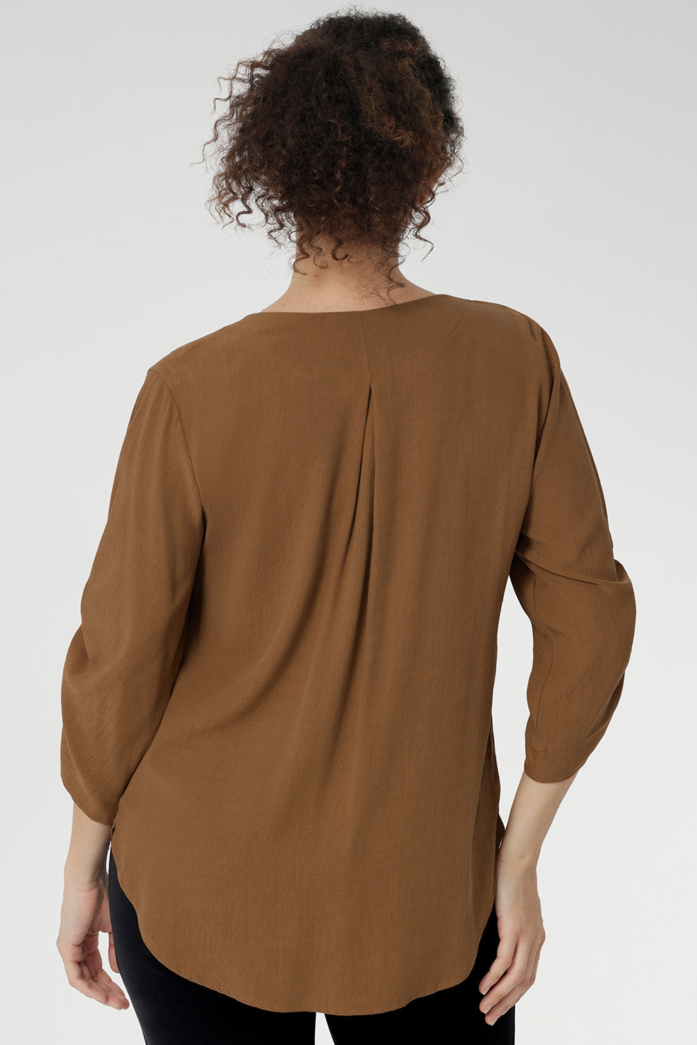 The back is finished with a subtle pleat for a touch of structure and flow. With beautifully ruched ¾ sleeves that fall gracefully toward the front of the arm.