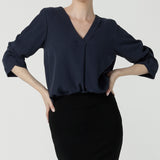 A size 10 woman wears the Terry Top in Bluestone, a Navy tencel shirt that is breathable and soft. Made in high quality fabric in Australia. Soft V-neckline and ruched sleeves. Made in Australia for women size 8-24. 