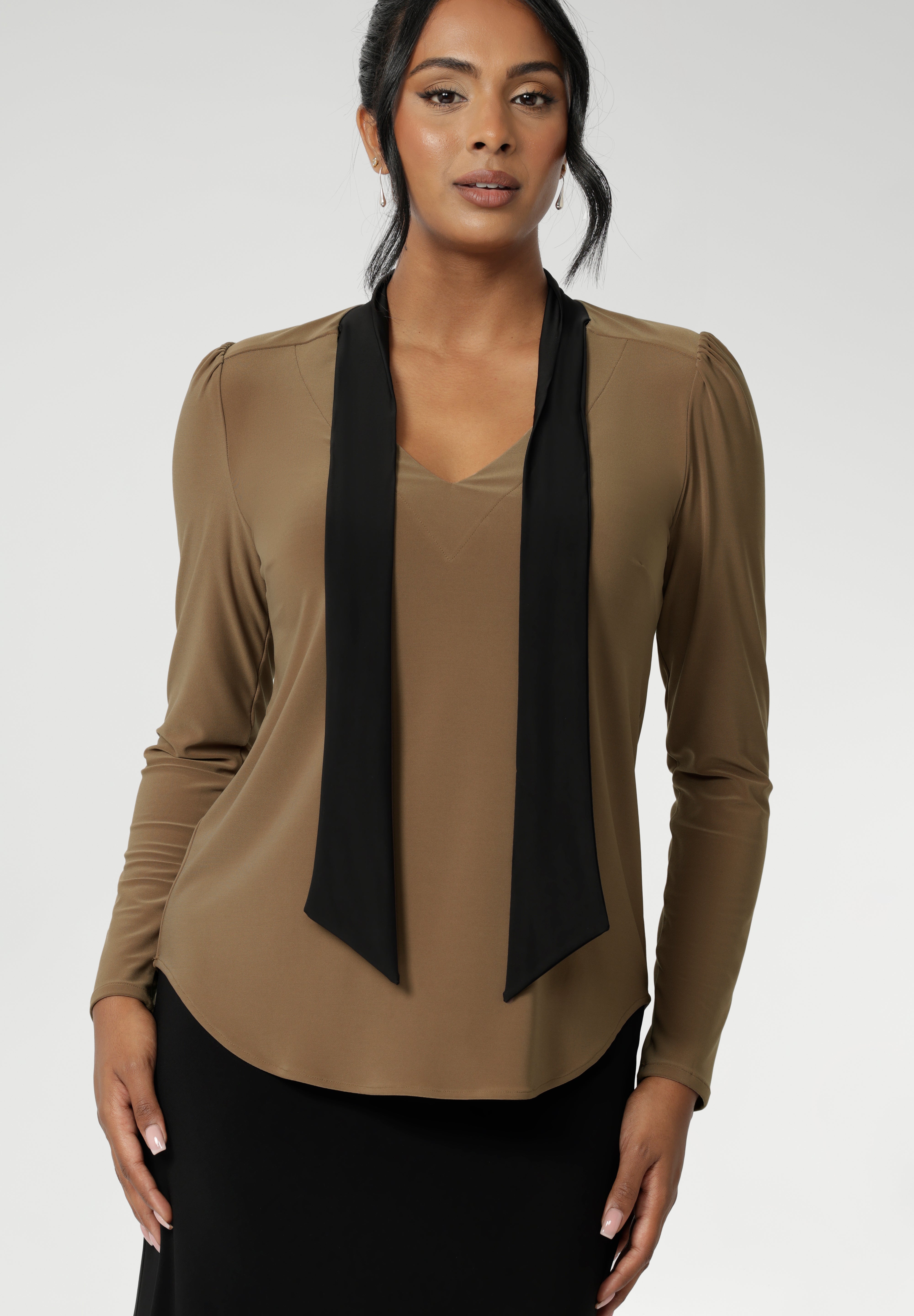 The soft V-neckline is accented by attached neck ties in a warm coffee tone, offering styling versatility—wear them tied for a polished office look or leave them loose for a more relaxed, contemporary feel. Full-length sleeves with gentle gathers at the shoulders add a touch of femininity, while the shoulder yoke and tailored tuck at the back create subtle shape without feeling structured.