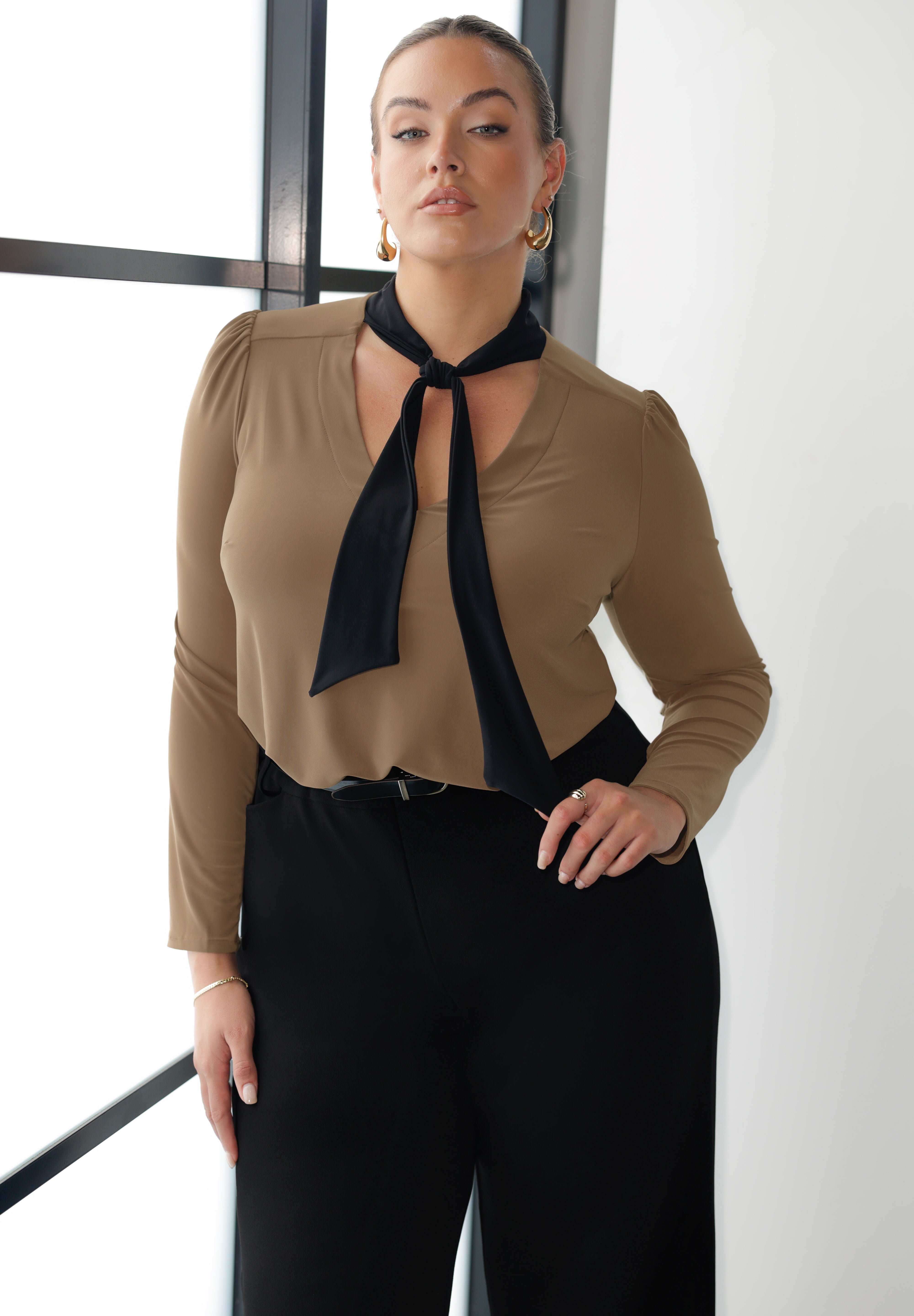 The Thom Top in black with contrasting coffee-coloured ties brings a refined edge to everyday dressing. Designed for women who want style that works across occasions, this jersey top blends comfort with quiet sophistication. Available in sizes 8-24.