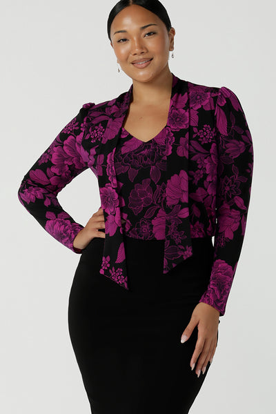 A size 10 model wears the Thom top in Fuchsia Flora is sophisticated and so versatile. Tie the neck-ties to the front for a day in the office or leave the ties open for your next event.