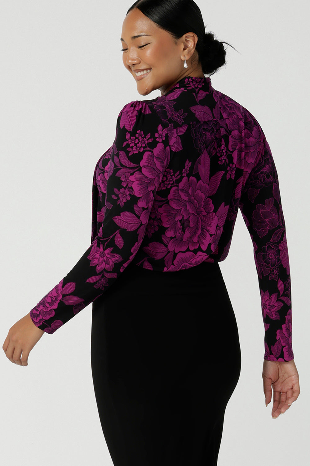 Back view of a size 10 model wears the Thom top in Fuchsia Flora is sophisticated and so versatile. Tie the neck-ties to the front for a day in the office or leave the ties open for your next event.