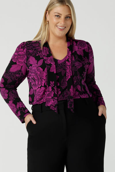A size 18 model wears the Thom top in Fuchsia Flora is sophisticated and so versatile. Tie the neck-ties to the front for a day in the office or leave the ties open for your next event. Made in Australia for women size 8 - 24. 