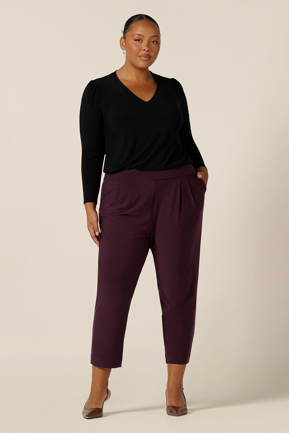 A size 18, plus size woman wears tapered leg, dropped crotch pants in stretch jersey with a black, long sleeve jersey top - both made in Australia.