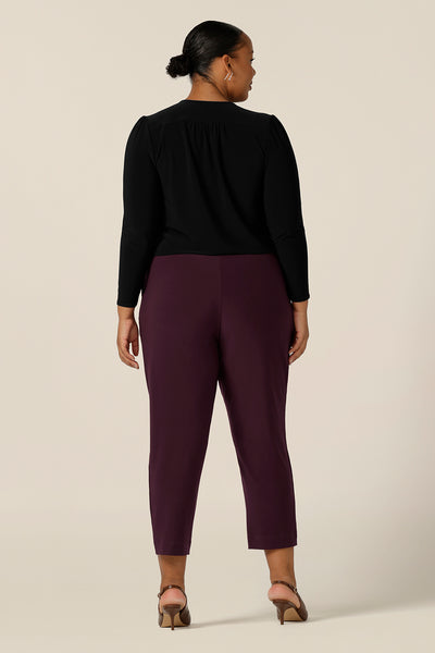 back view of a size 18, plus size woman wearing tapered leg, dropped crotch pants in stretch jersey with a black, long sleeve jersey top - both made in Australia.