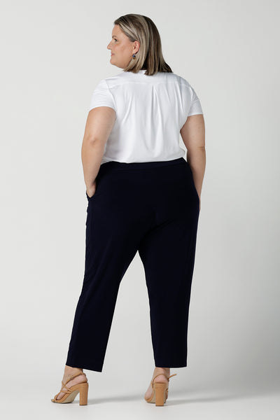 Back view of a size 18 curvy woman wears the Tobie pant in Navy. A comfortable navy work pant with pleat front and pocket detail. Great work pants in soft Jersey. Great for petite to plus size. Made in Australia for women size 8 - 24.