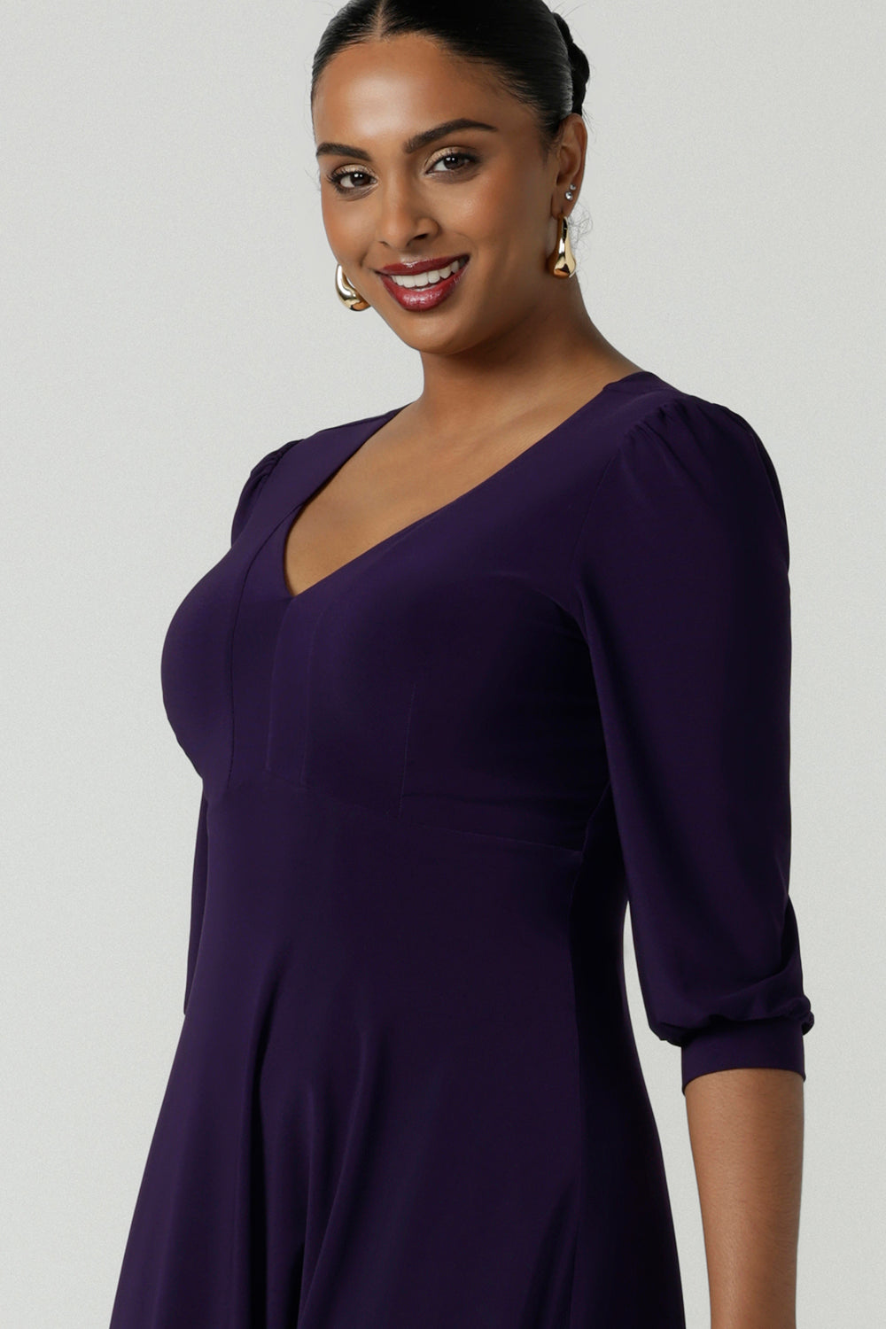 Close up of a woman wearing a size 10 Amethyst purple Tracey dress in comfortable jersey. A great work wear style that is easy care with an empire line and 3/4 sleeves. Below knee length with a v-neckline. Petite to plus size size 8-24.