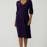 A size 10 woman wears a Amethyst purple Tracey dress in comfortable jersey. A great work wear style that is easy care with an empire line and 3/4 sleeves. Below knee length with a v-neckline. Petite to plus size size 8-24.