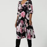 A size 10 woman wears the Tracey Dress in Night bloom. A Empire Line Dress with a floral print on a black base. Comfortable jersey design. Made in Australia for women size 8-24. Petite to plus size women. 