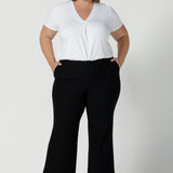 Great pants for curvy women, these flared leg, cropped pants are tailored for smart casual office wear. Worn with a V-neck, short sleeve top in white, and shown on a size 18 woman, these plus size black pants are made in Australia by Australian and New Zealand women's clothing brand, Leina & Fleur. Shop quality pants in sizes 8 to 24 in their online fashion boutique!