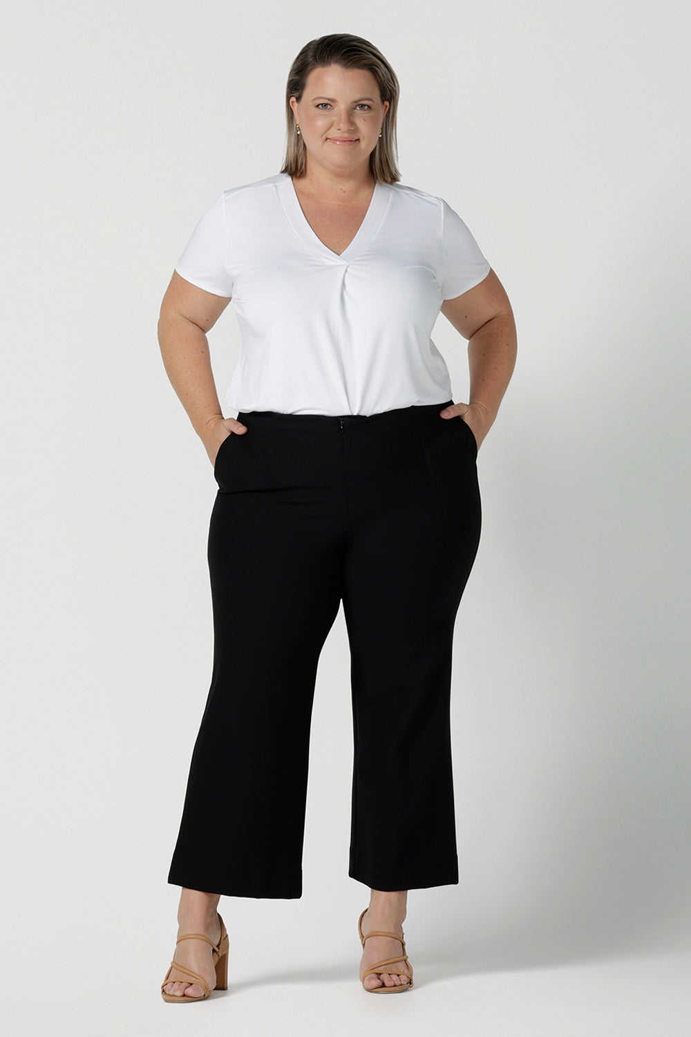 Great pants for curvy women, these flared leg, cropped pants are tailored for smart casual office wear. Worn with a V-neck, short sleeve top in white, and shown on a size 18 woman, these plus size black pants are made in Australia by Australian and New Zealand women's clothing brand, Leina & Fleur. Shop quality pants in sizes 8 to 24 in their online fashion boutique!
