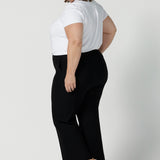 Back view of Troy pants for curvy women, these flared leg, cropped pants are tailored for smart casual office wear. Worn with a V-neck, short sleeve top in white, and shown on a size 18 woman, these plus size black pants are made in Australia by Australian and New Zealand women's clothing brand, Leina & Fleur. Shop quality pants in sizes 8 to 24 in their online fashion boutique!