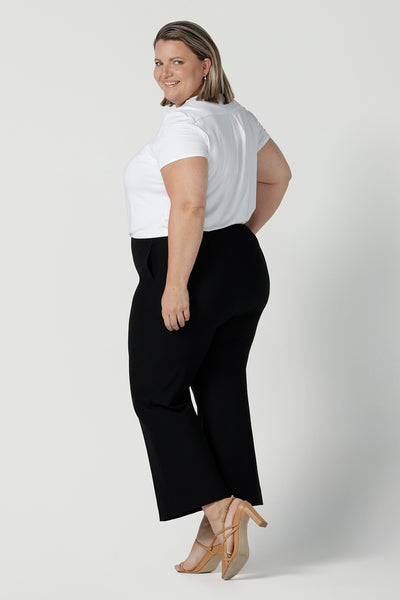 Back view of Troy pants for curvy women, these flared leg, cropped pants are tailored for smart casual office wear. Worn with a V-neck, short sleeve top in white, and shown on a size 18 woman, these plus size black pants are made in Australia by Australian and New Zealand women's clothing brand, Leina & Fleur. Shop quality pants in sizes 8 to 24 in their online fashion boutique!