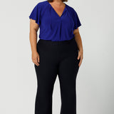 Great pants for curvy women, these flared leg, cropped pants are tailored for smart casual office wear. Worn with a V-neck, flutter sleeve top in cobalt blue, and shown on a size 18 woman, these plus size navy blue pants are made in Australia by Australian and New Zealand women's clothing brand, Leina & Fleur. Shop quality pants in sizes 8 to 24 in their online fashion boutique!