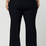 Back view of good pants for curvy women. These flared leg, cropped pants are tailored with back leg seams for smart casual office wear. Worn with a V-neck, flutter sleeve top in cobalt blue, and shown on a size 18 woman, these plus size navy blue pants are made in Australia by Australian and New Zealand women's clothing brand, Leina & Fleur. Shop quality pants in sizes 8 to 24 in their online fashion boutique!