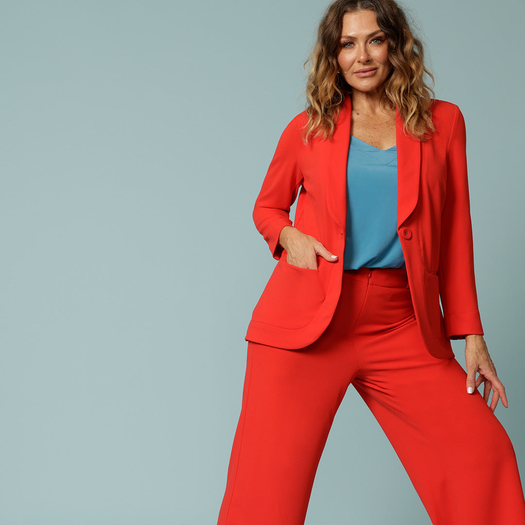 Top of every over 40s style hit list should be this, a Tangerine red suit women will love! Showing a tangerine red workwear blazer worn with a blue summer top with wide straps, and matching tangerine red pants to complete the suit set. Made in Australia shop this women's pant suit at Australian and New Zealand women's clothes brand, Leina & Fleur.