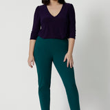 A good workwear outfit for petite height women, a size 12 woman wears tapered leg, green work pants with a 3/4 jersey top in amethyst purple. Good pants for work, these trousers are made from stretchy jersey and are comfortable for all-day wear. Made in Australia by Australian and New Zealand women's clothes label, Leina & Fleur, shop easy-care workwear for petite to plus size women. 