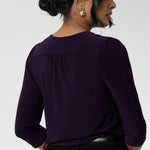 Close up image of Amethyst coloured woman's workwear shirt displays the tailored details such as centre-back gathers and shoulder tucks. Size 10 woman workwear shirt is worn tucked into black tailored pants with belt loops.