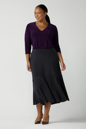 Size 16 wears the Berit Maxi skirt in Charcoal. A women's jersey work skirt with pockets in a charcoal colour. Made in Australia for women size 8 - 24. Styled back with a Purple Amethyst Vida top with 3/4 sleeves and a v-neckline. 